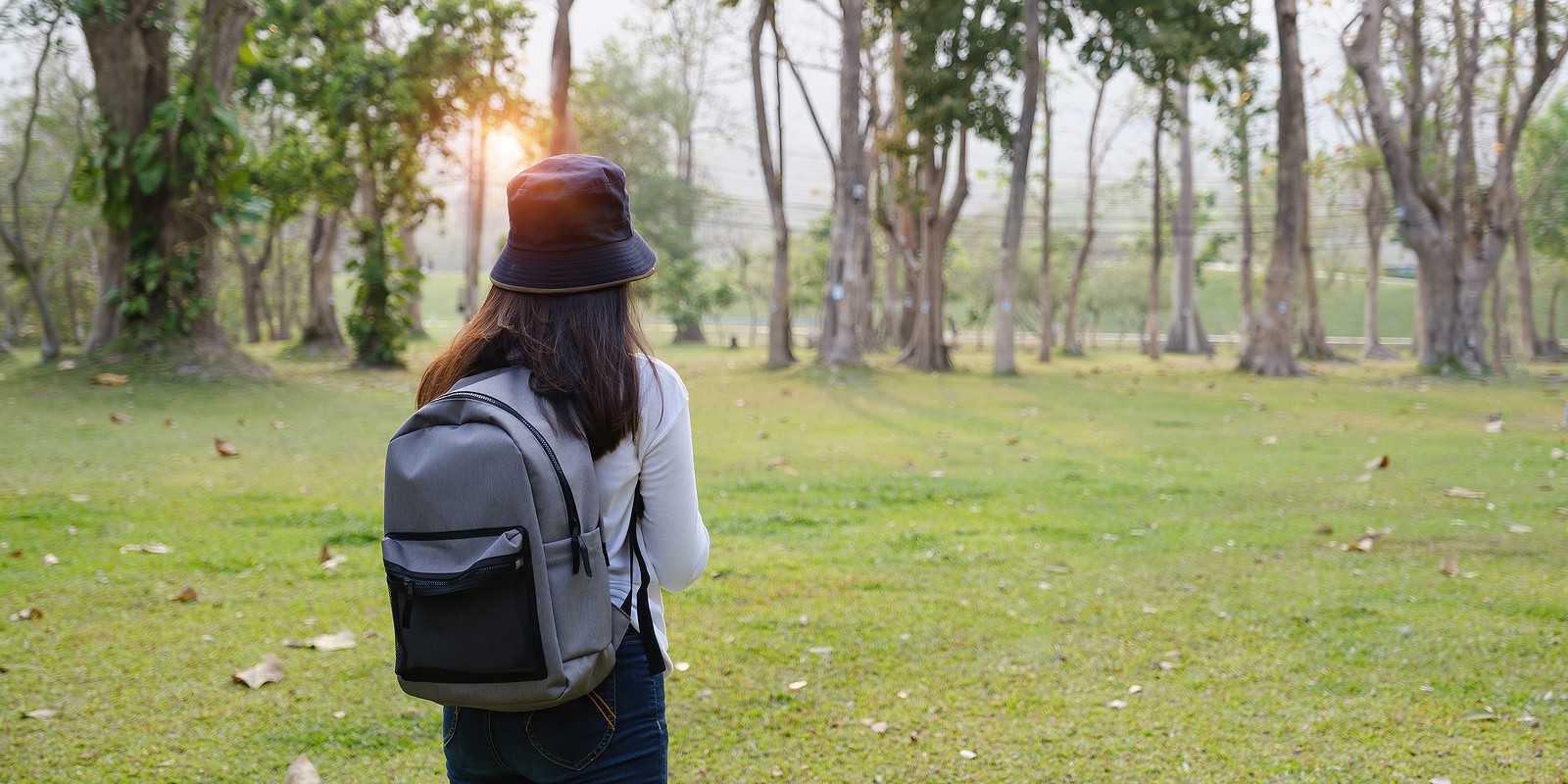 Image of a young woman wearing a backpack and looking out at a green field. This image represents what a college student in need of an anxiety therapist in Nashville, TN may look like. | 37204 | 37212 | 37129