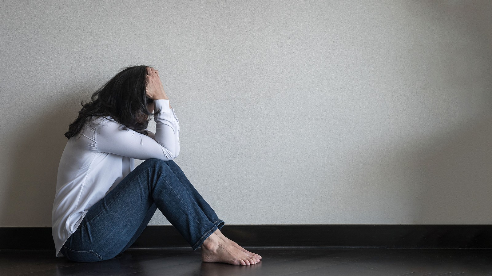Image of a woman sitting on the floor holding her head in her hands. This image represents someone suffering from a panic attack and in need of an anxiety therapist in Nashville, TN. 37027 | 37212 | 37204