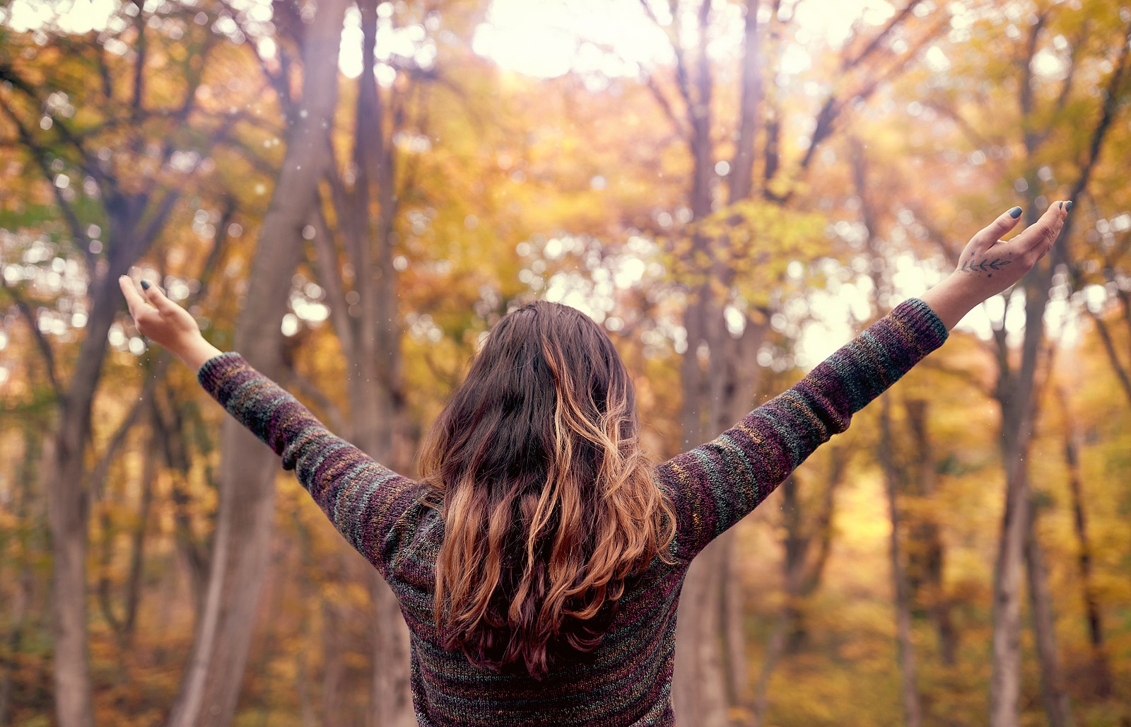 Image of a young woman holding her arms out to her sides while standing in a forest. This image depicts the relief you can find when meeting with an anxiety therapist for anxiety treatment in Nashville, TN. 37205 | 37204