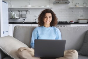 Image of a young woman using a laptop and smiling. This image represents how anxiety treatment in Nashville, TN can help decrease college student anxiety. | 37130 | 37916