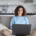 Image of a young woman using a laptop and smiling. This image represents how anxiety treatment in Nashville, TN can help decrease college student anxiety. | 37130 | 37916