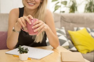 Image of a young woman holding a pink coffee mug and smiling. This image demonstrates the relief from anxiety symptoms that can be found working with an anxiety therapist in Nashville, TN. 37203 | 37383