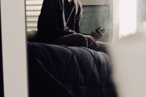 Image of a man having a telehealth session on his phone. This image illustrates how college students can have privacy with an online therapist in Nashville, TN. Young adults across the state can meet with one using online therapy in Tennessee. | 37203 | 37129